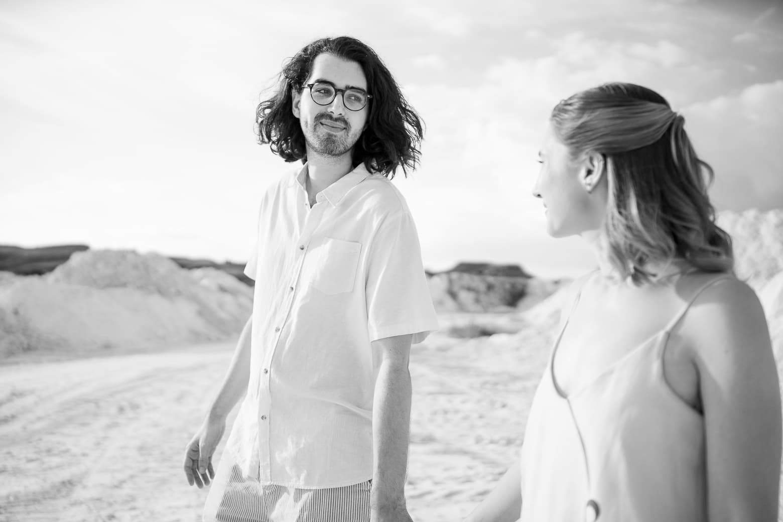 Letícia e Bruno caminhando nas dunas de areia branca, em preto e branco